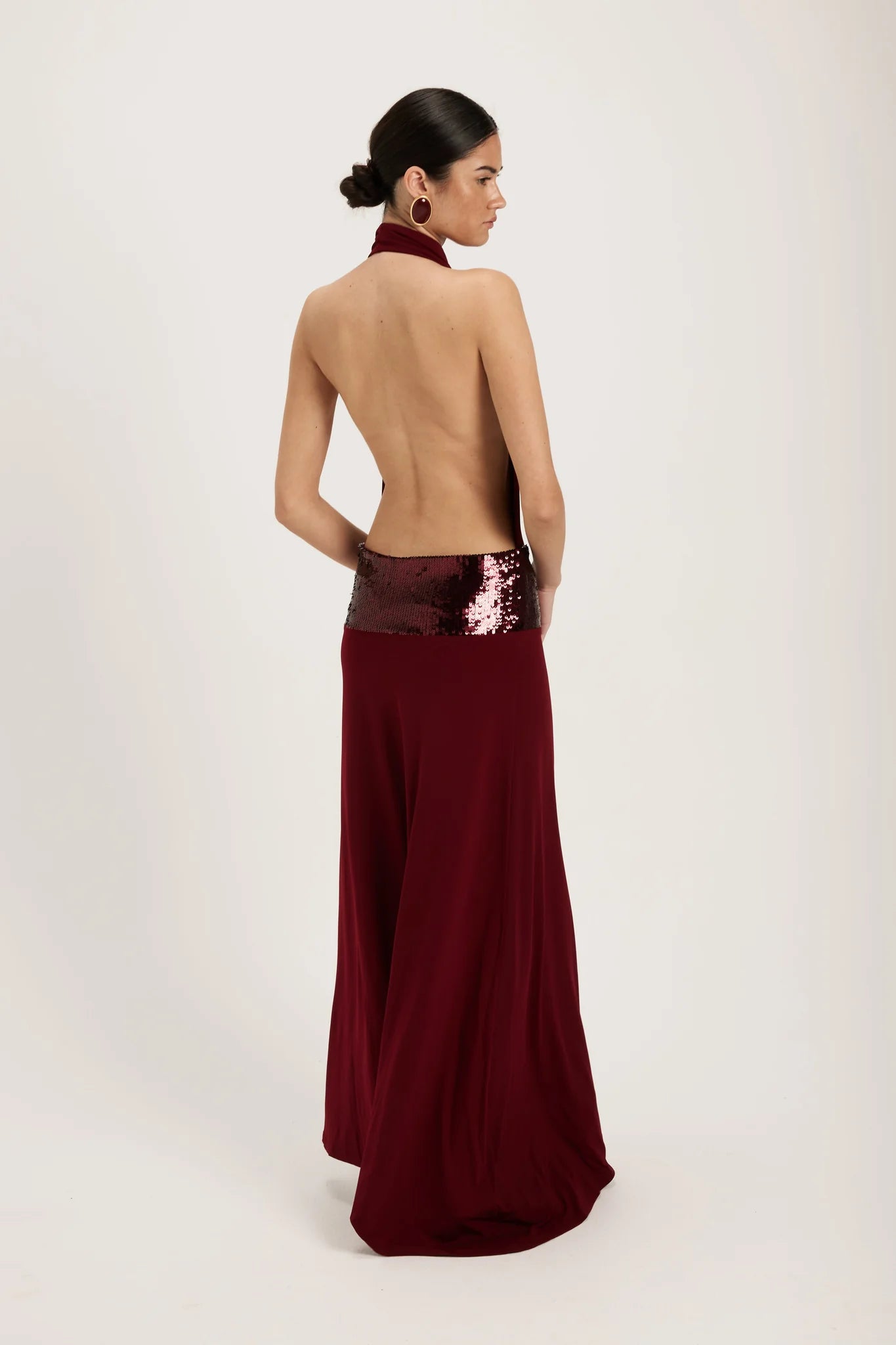 Ance Gria Adele Gown Hire in Wine. A backless, deep red gown with an embellished sequin waistband. Available Australia-wide.