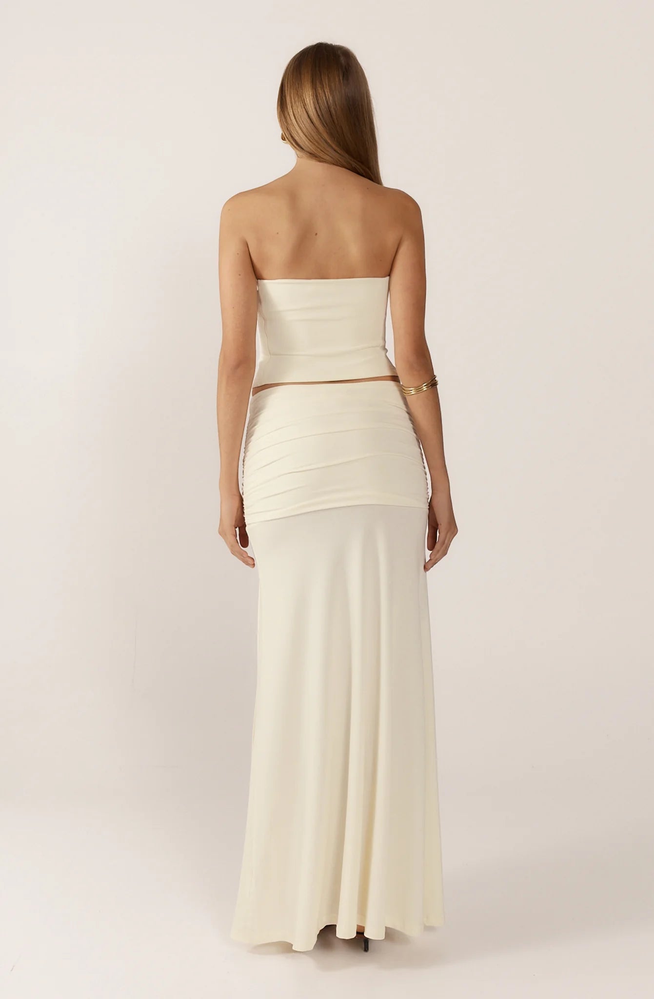 Ance Gria Jude Full Set in Ivory for hire. Bandeau corset top with 3D floral detailing and sheer draped maxi skirt with low-rise, sarong-style hipline.